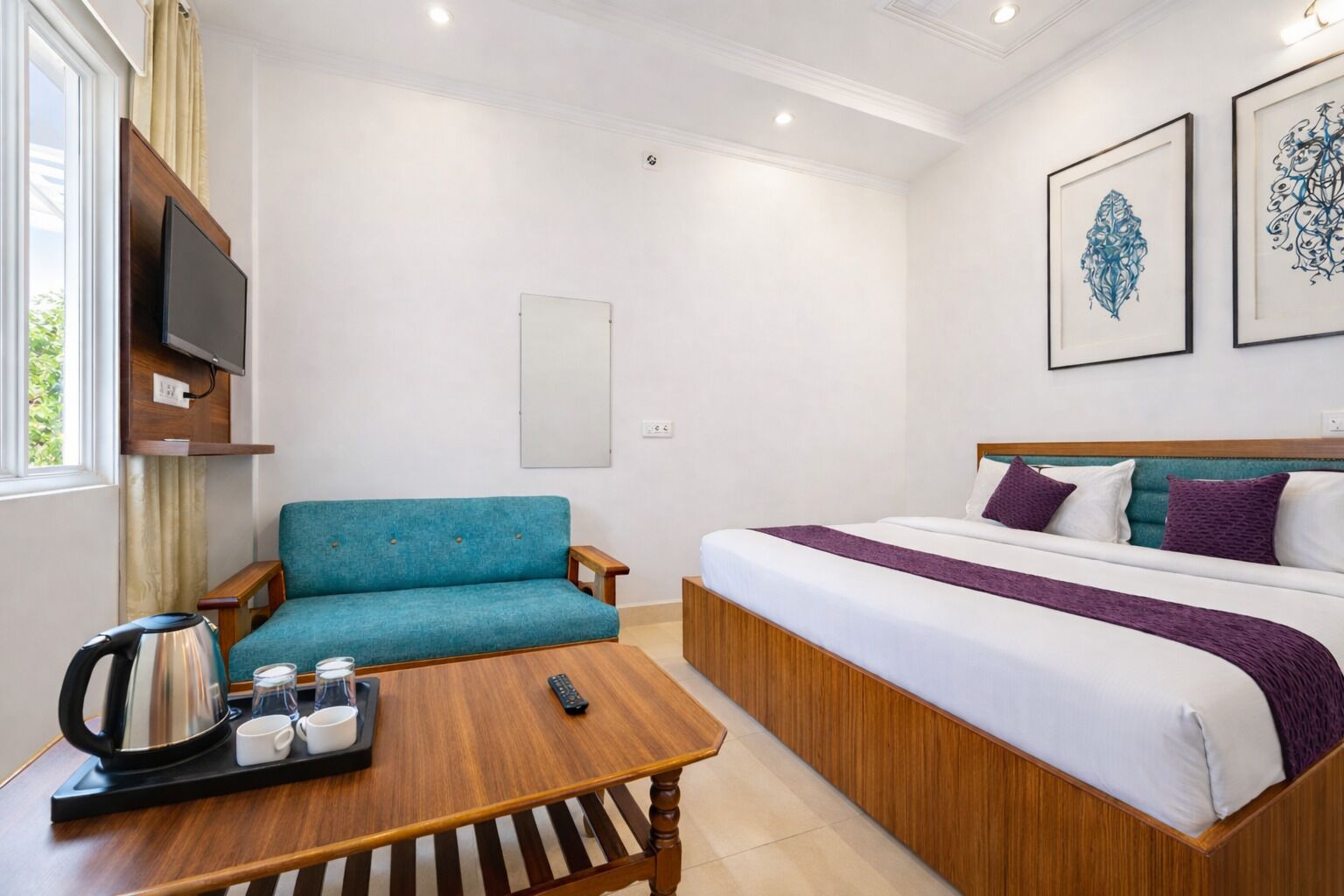 A hotel room with a bed, a sofa, a coffee table, and a TV.