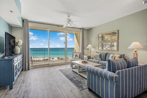 A living room with a large sliding glass door leading to a balcony with a view of the ocean. - Gulf-Front Condo | Huge Pool + Balcony Views | Sleeps 6 | Shores of Panama (Panama City Beach)