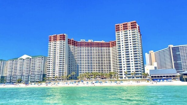 A beachfront hotel with multiple high-rise buildings, a sandy beach, and clear blue waters.