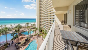 A hotel balcony with a view of a beach and a swimming pool.