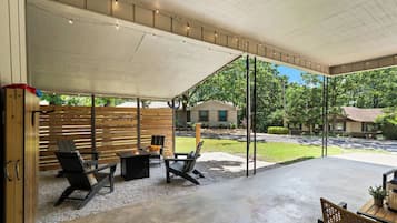 An outdoor patio area with a covered seating area, a fire pit, and a view of the surrounding neighborhood.