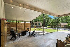 An outdoor patio area with a covered seating area, a fire pit, and a view of the surrounding neighborhood.