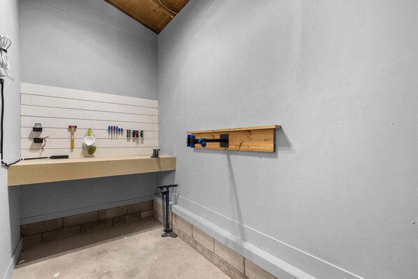 A bathroom with a white vanity, a wooden shelf, and various toiletries.