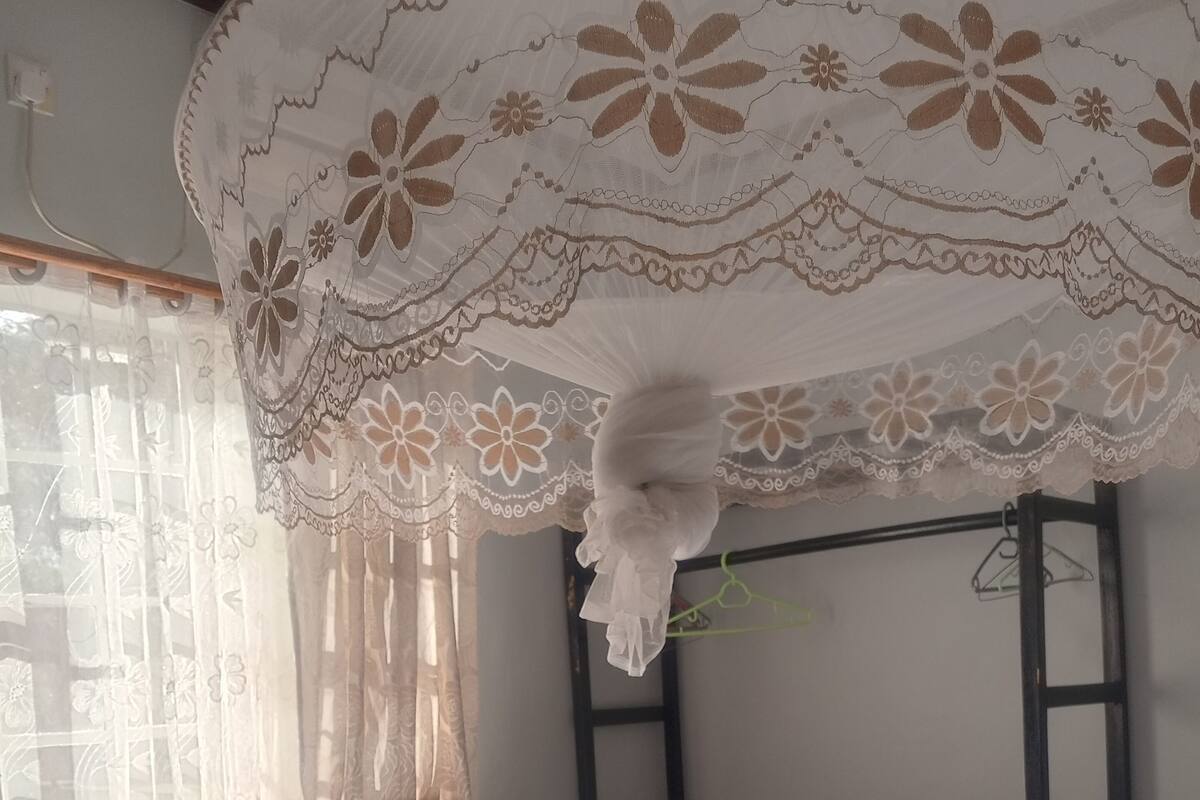 Cama com roupa de cama branca, um cobertor roxo e toalhas dobradas.