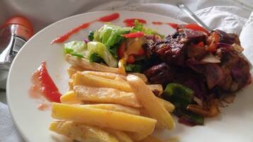 A plate with grilled meat, vegetables, and fries.