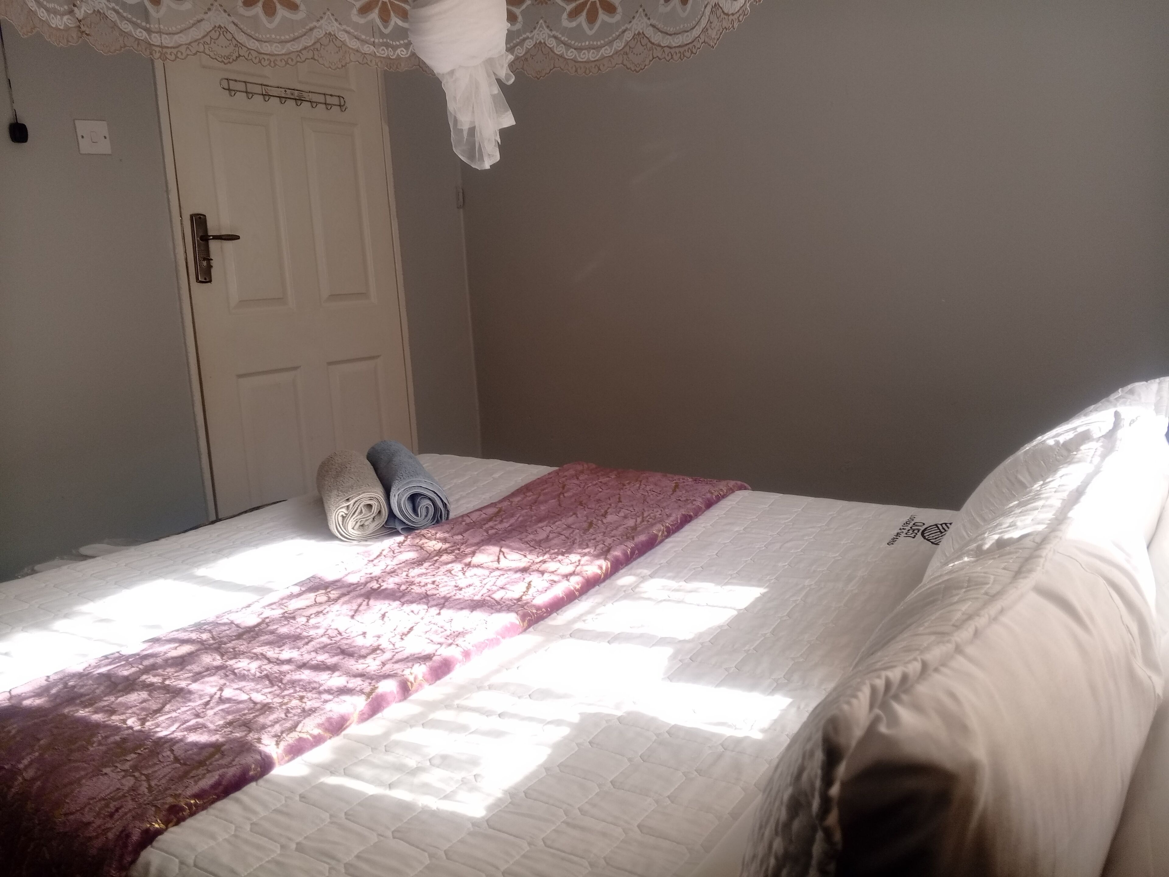 A bedroom with a bed, a white door, and a window.