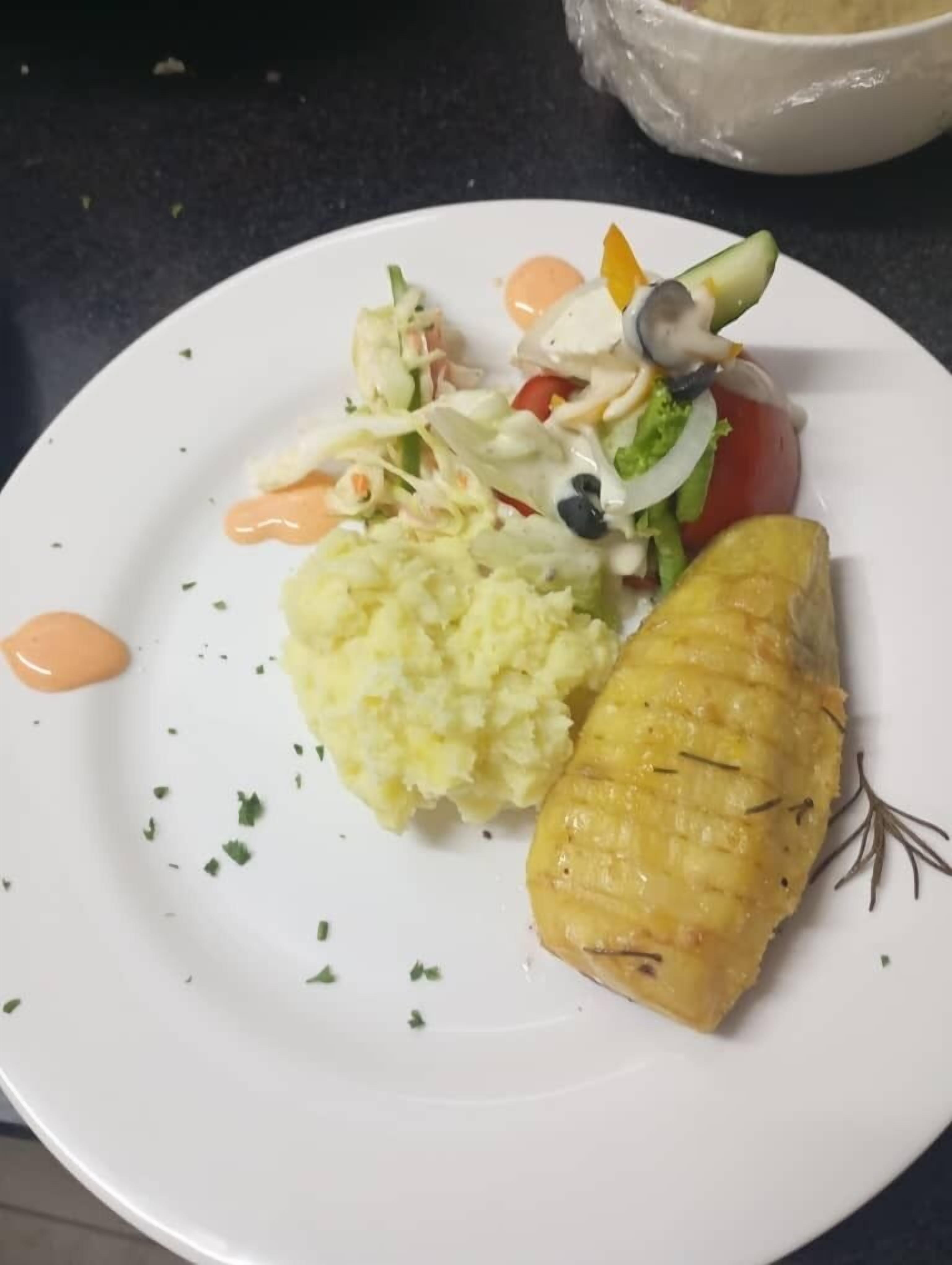Un plato con pescado a la plancha, ensalada de col y puré de patatas.