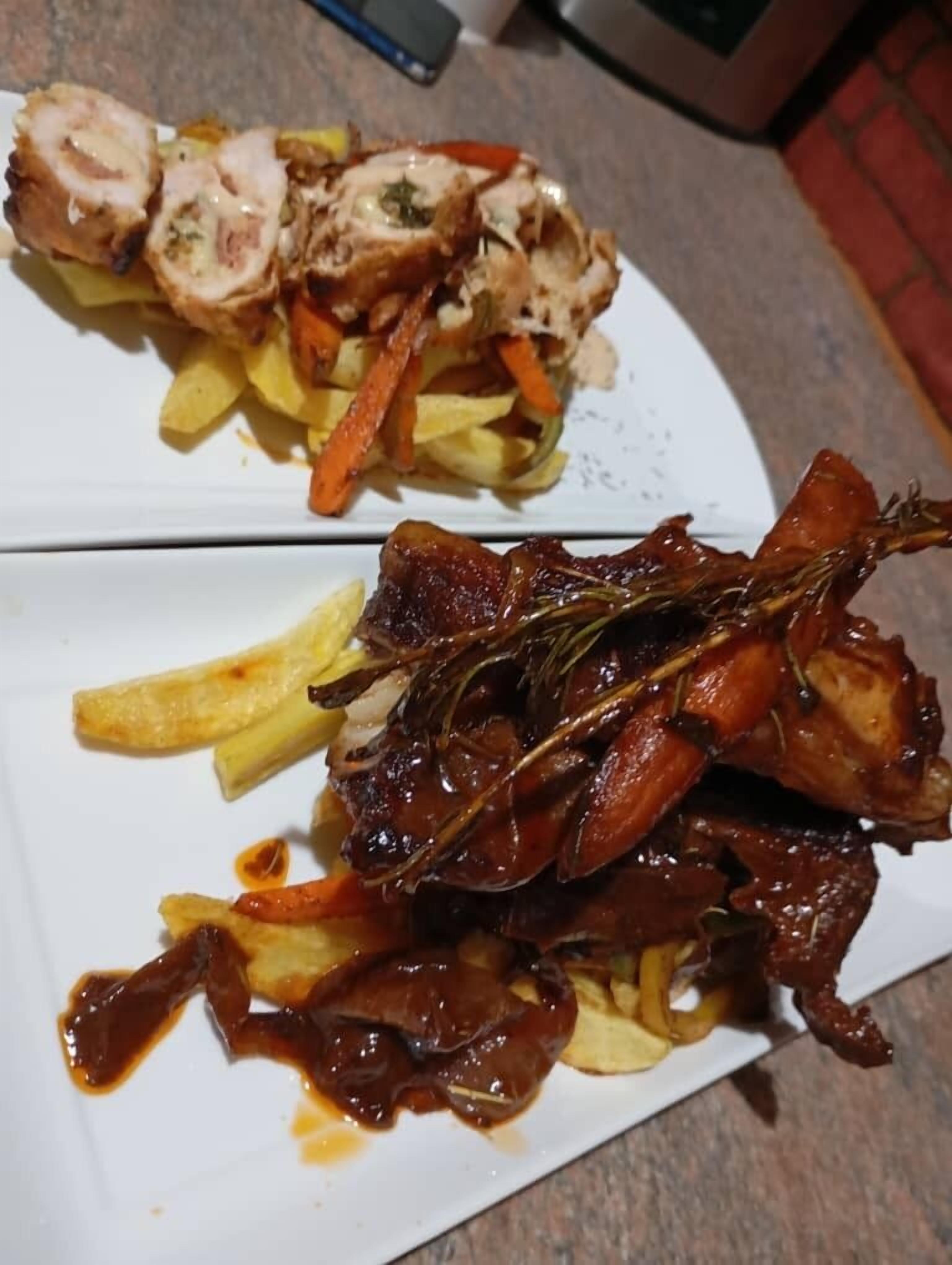 A plate of food with sliced meat, fries, and carrots.