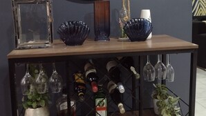 A wooden table with a mirror, decorative bowls, and wine bottles. - Quest Lodges and Safaris (Lilongwe)