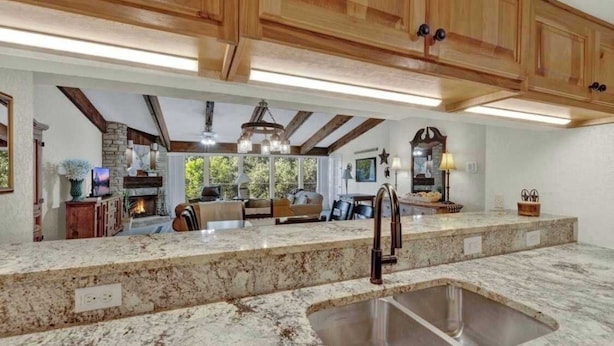 A kitchen with granite countertops, wooden cabinets, and a large island with a sink.