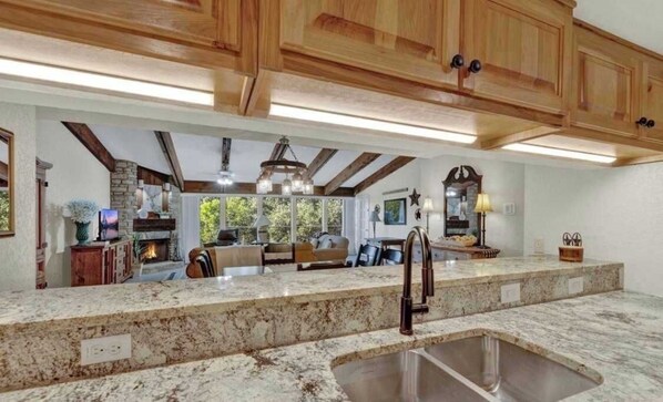 A kitchen with granite countertops, wooden cabinets, and a large island with a sink.