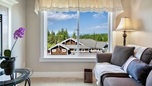 A room with a large window, a view of houses, a round glass table, a potted plant, and a sofa. - Stylish Bellevue 5BR/2.5BA Upper Unit | LEGO Fun! (Bellevue)