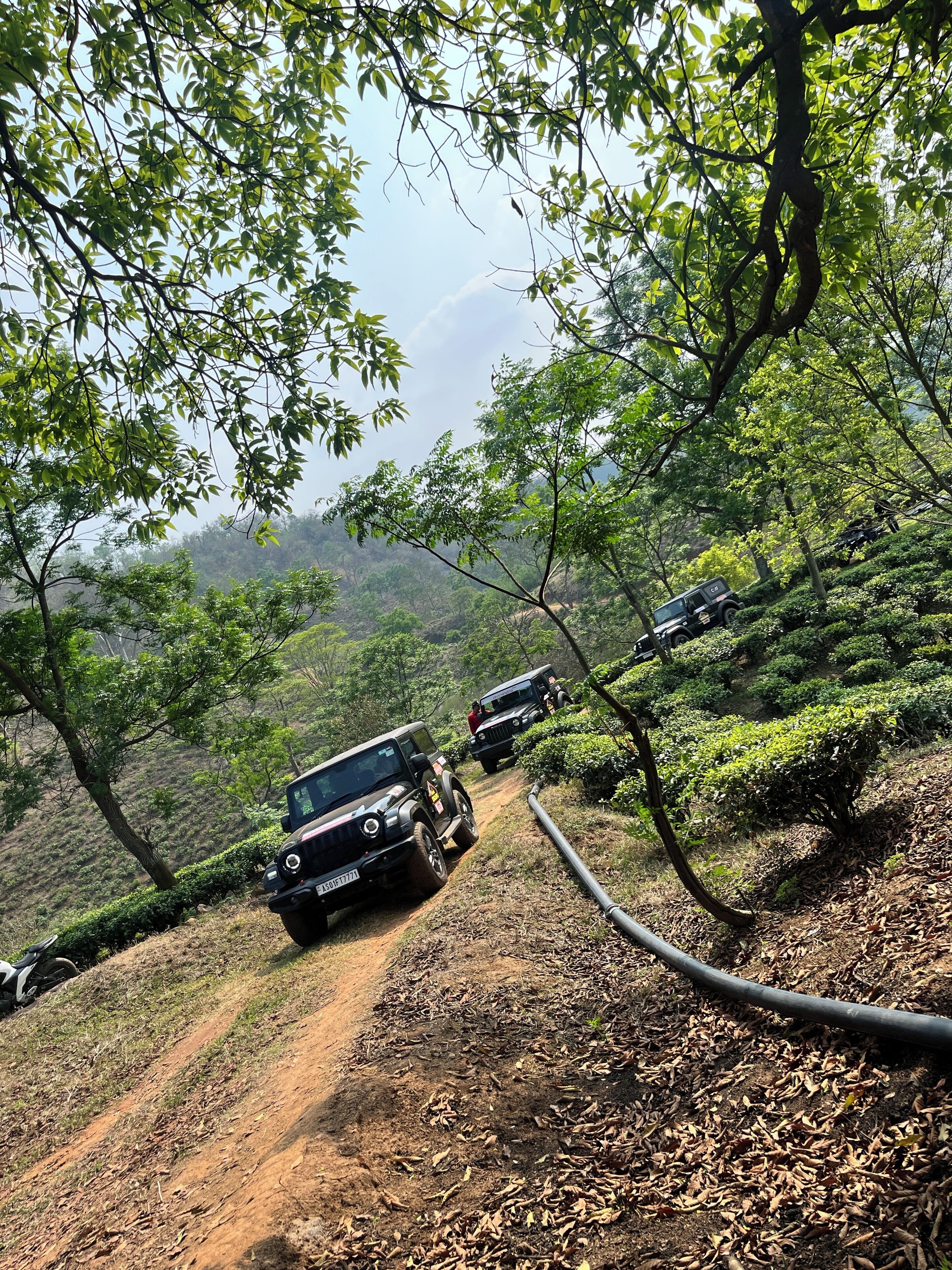 A dirt path with vehicles and a hose.