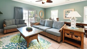A living room with a sofa, coffee table, and a dining area with a table and chairs.