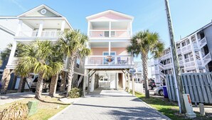 A multi-story residential building with balconies, a covered walkway, and a parking area.