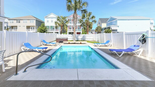 A swimming pool with blue lounge chairs and palm trees.