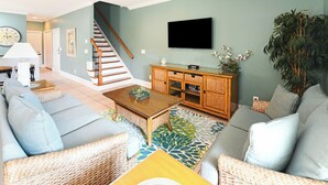 A living room with a sofa, coffee table, and a television on a wall.