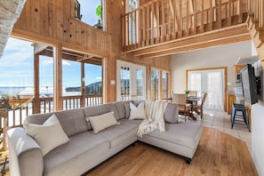 Un interior de madera con sofá, zona de comedor y televisor.