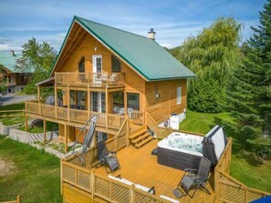 Eine Holzhütte mit Balkon, Whirlpool und einer Terrasse.