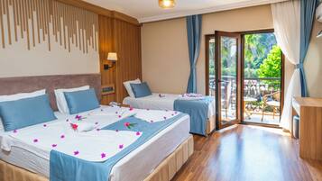A hotel room with two beds, a wooden headboard, a balcony with a view, and a wooden floor.
