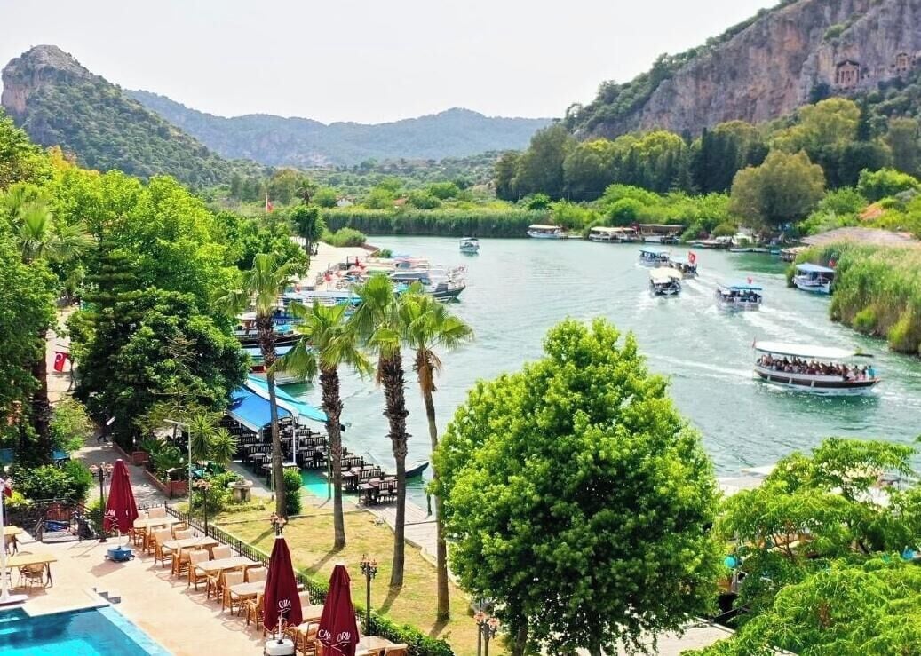 A luxury hotel with a pool, outdoor seating, and boats on a river.