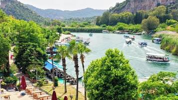 A luxury hotel with a pool, outdoor seating, and boats on a river.