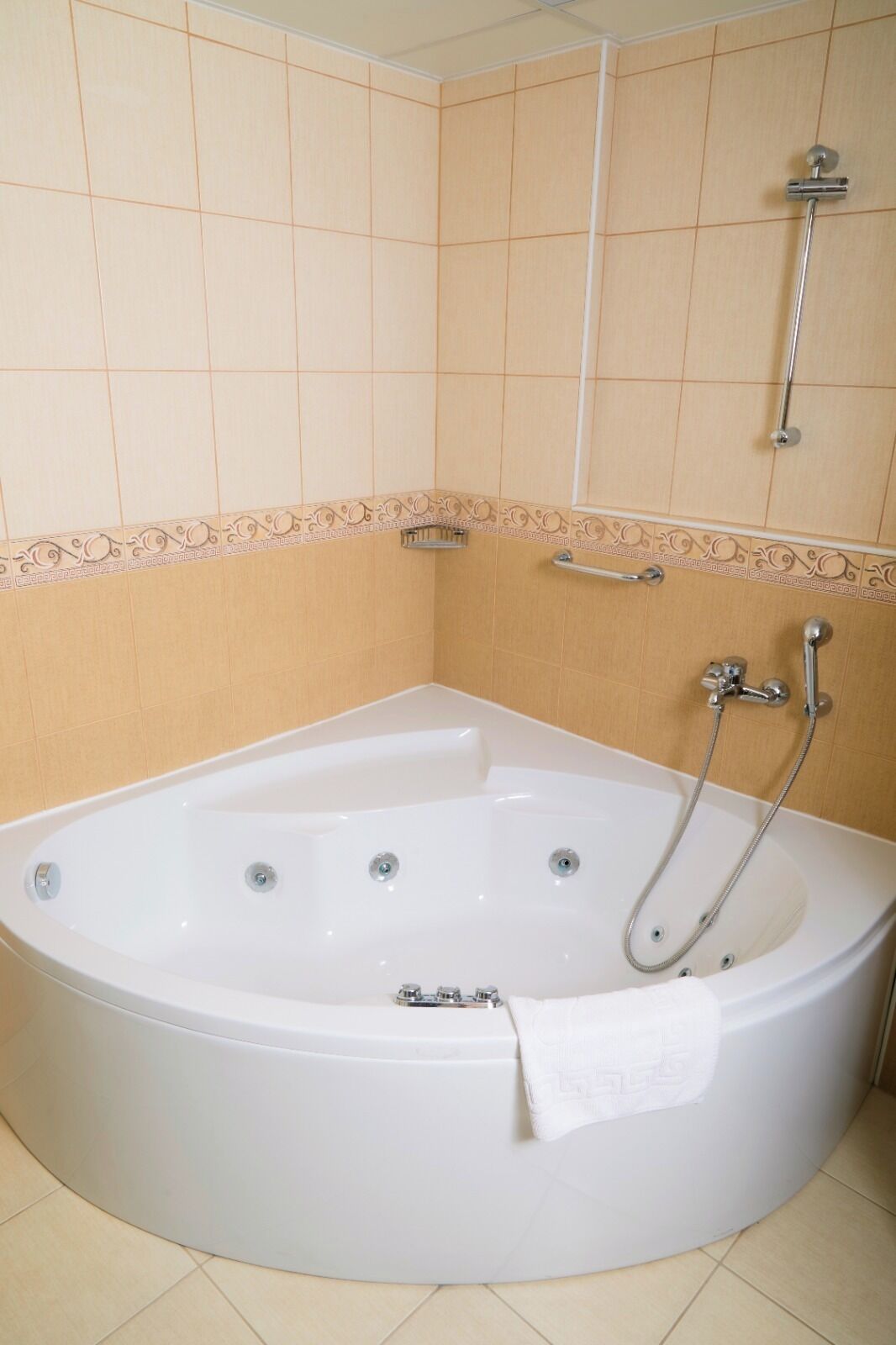 A large, white, freestanding bathtub with a single faucet and a handheld showerhead.
