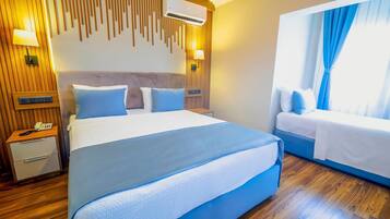 A hotel room with a large bed, a smaller bed, wooden paneling, a wall-mounted air conditioner, a bedside table with a phone, and a window with curtains.