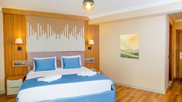 Quarto de hotel com cama grande, painel de parede de madeira, duas luminárias laterais, um quadro e piso de madeira.