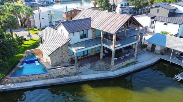 Ein mehrstöckiges Haus mit Pool, Steinaußenfassade und einer Anlegestelle im Wasser.
