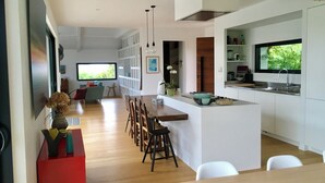 A modern kitchen with a central island, white cabinetry, and a large window.