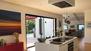 A modern kitchen with a central island, a dining area with a sofa, and a large painting on the wall.