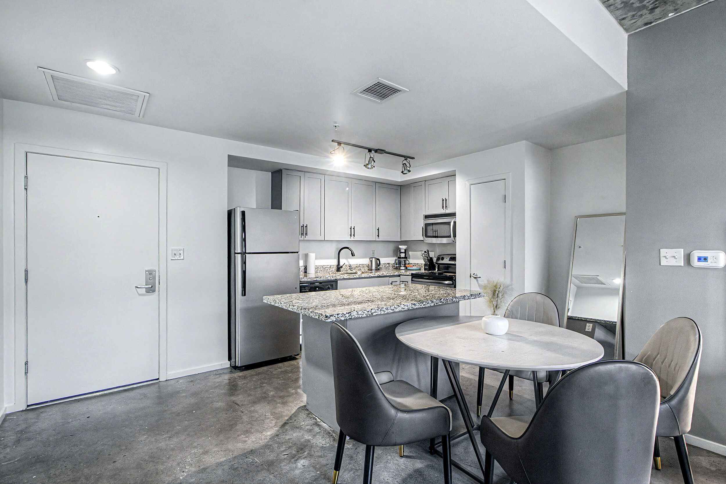 A modern kitchen with a central island, stainless steel appliances, and a dining area with two chairs.