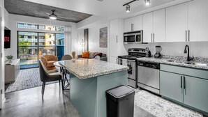 Une cuisine moderne dotée d’un îlot central, d’appareils électroménagers intégrés et offrant une vue sur l’extérieur.