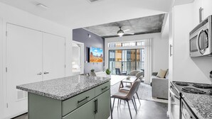 Une cuisine moderne dotée de plans de travail en granit, d’une cuisinière encastrée et d’un coin repas avec un canapé et des chaises gris.