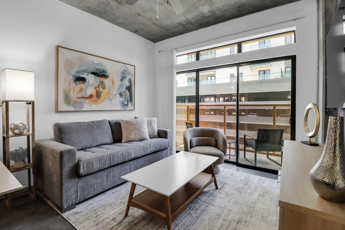 Ein modernes Wohnzimmer mit einem grauen Sofa, einem weißen Couchtisch und einem großen abstrakten Gemälde an der Wand.