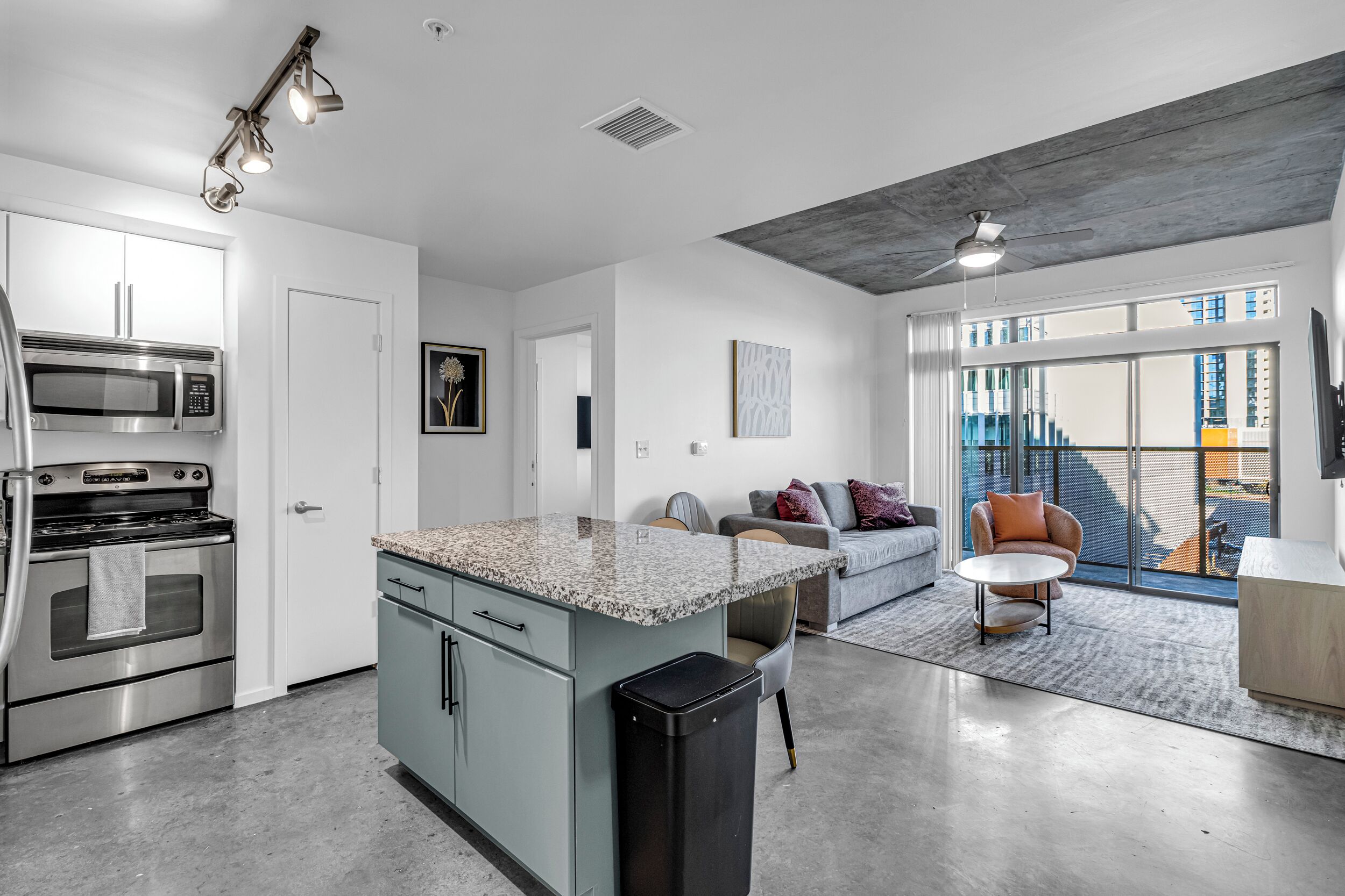 A modern kitchen with built-in appliances, a dining area with a round table, and a large window offering a view of the city.