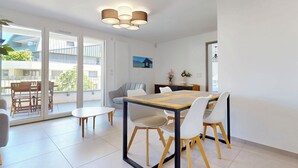 A modern dining area with a wooden table and chairs, a small round table, and a ceiling light fixture.