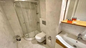 Ein modernes Badezimmer mit Duschkabine aus Glas, Toilette und Waschbecken mit Spiegel darüber.