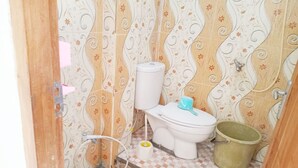 A bathroom with patterned wallpaper, a toilet, a bucket, and a checkered floor. - Kos Mama Ros (Labuan Bajo)