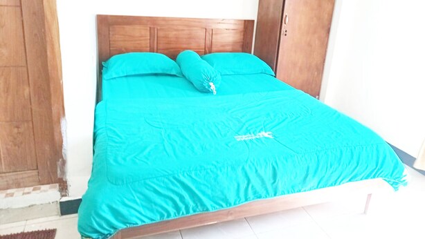 Un lit avec une tête de lit en bois et une couvre-lit de couleur turquoise.