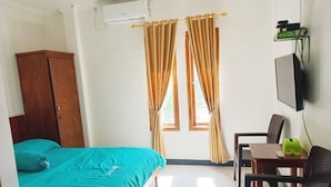 A room with a bed, a desk, a chair, a television, and a wardrobe. - Kos Mama Ros (Labuan Bajo)