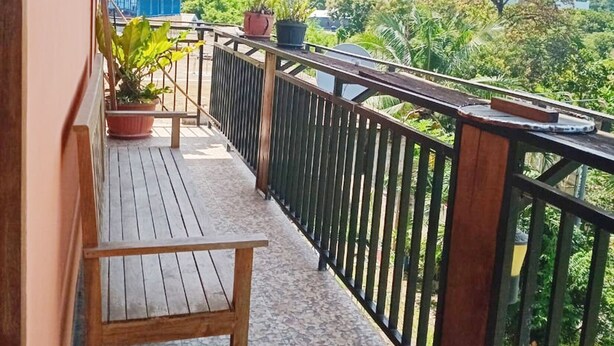 A balcony with a wooden floor, a chair, and potted plants. - Kos Mama Ros (Labuan Bajo)