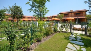 A courtyard with a pool, surrounded by a fence, and a building with a red-tiled roof.