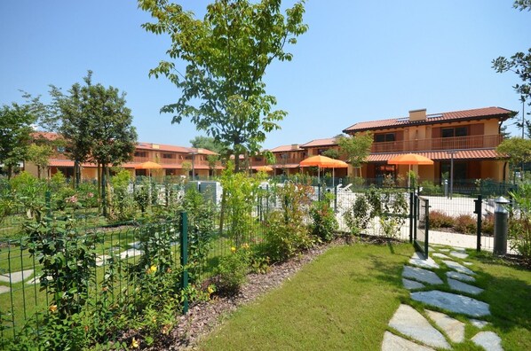 A courtyard with a pool, surrounded by a fence, and a building with a red-tiled roof.