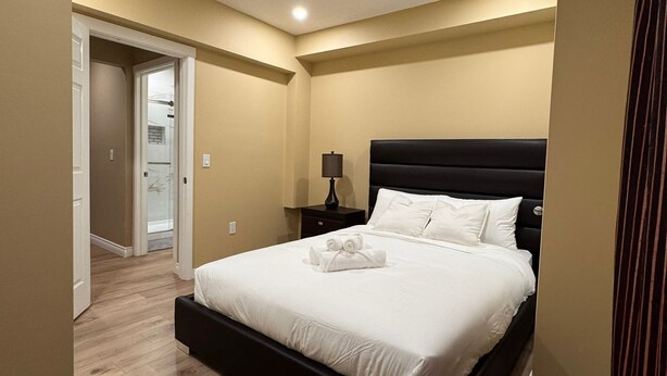Une chambre à coucher moderne avec un grand lit, une table de chevet et un luminaire au plafond.