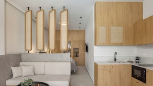 Una sala de estar moderna con un sofá, una mesa de centro y una zona de cocina con armarios de madera y horno integrado.
