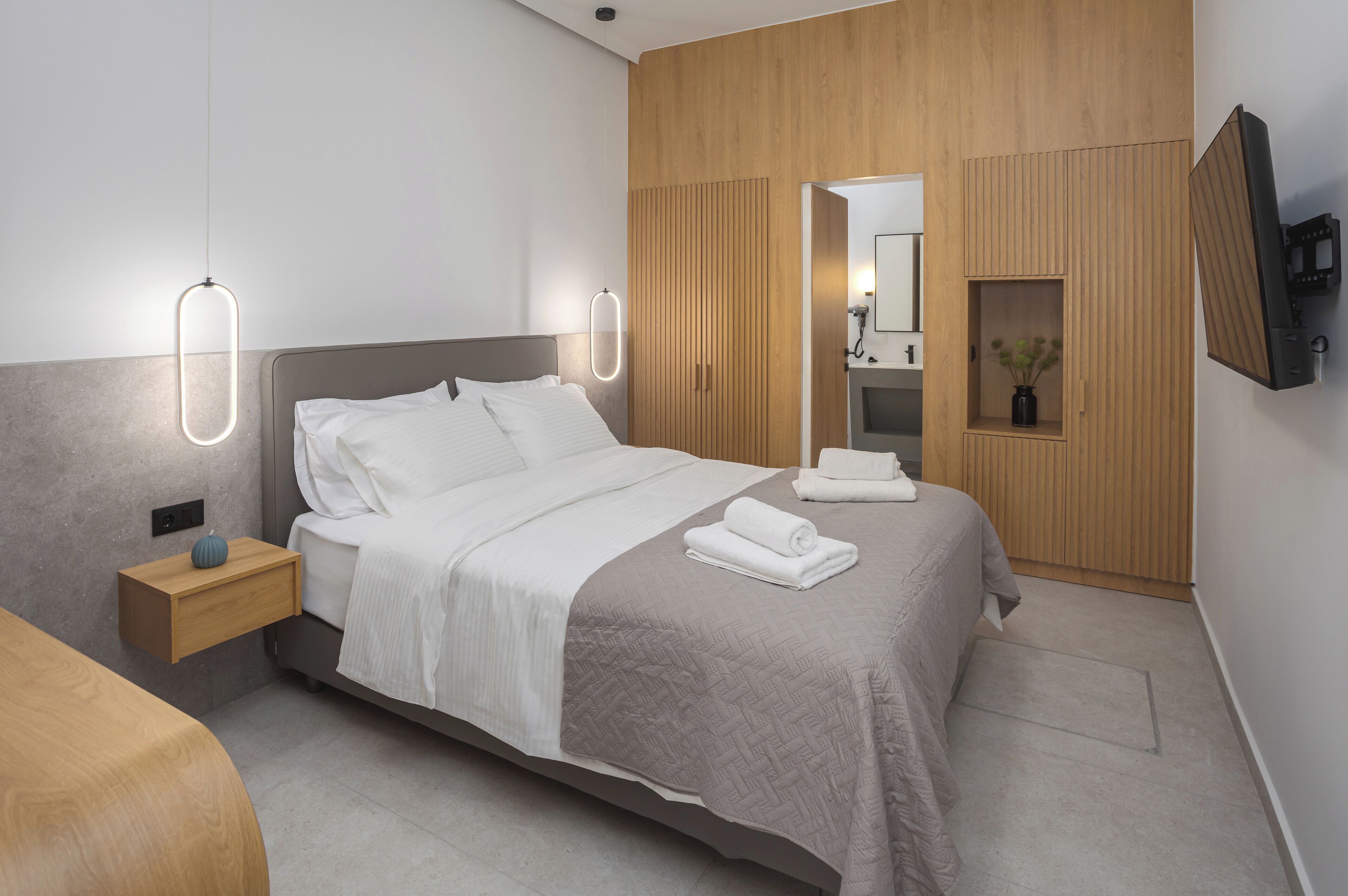 A modern hotel room with a bed, bedside table, and a built-in TV.