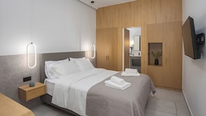 Una habitación de hotel moderna con una cama, mesita de noche y televisor integrado.
