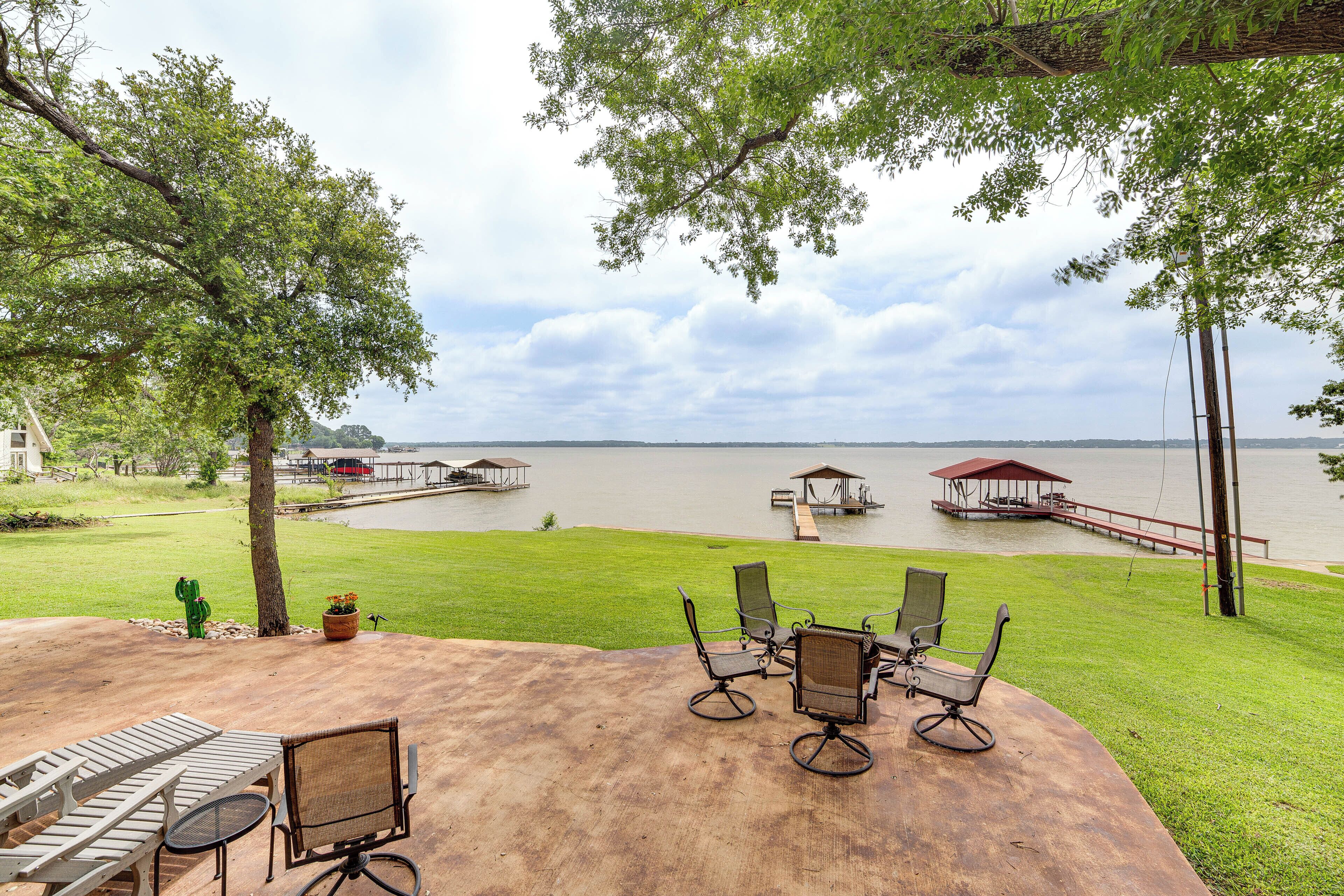 A patio with outdoor furniture overlooking a lake, a dock, and a gazebo.